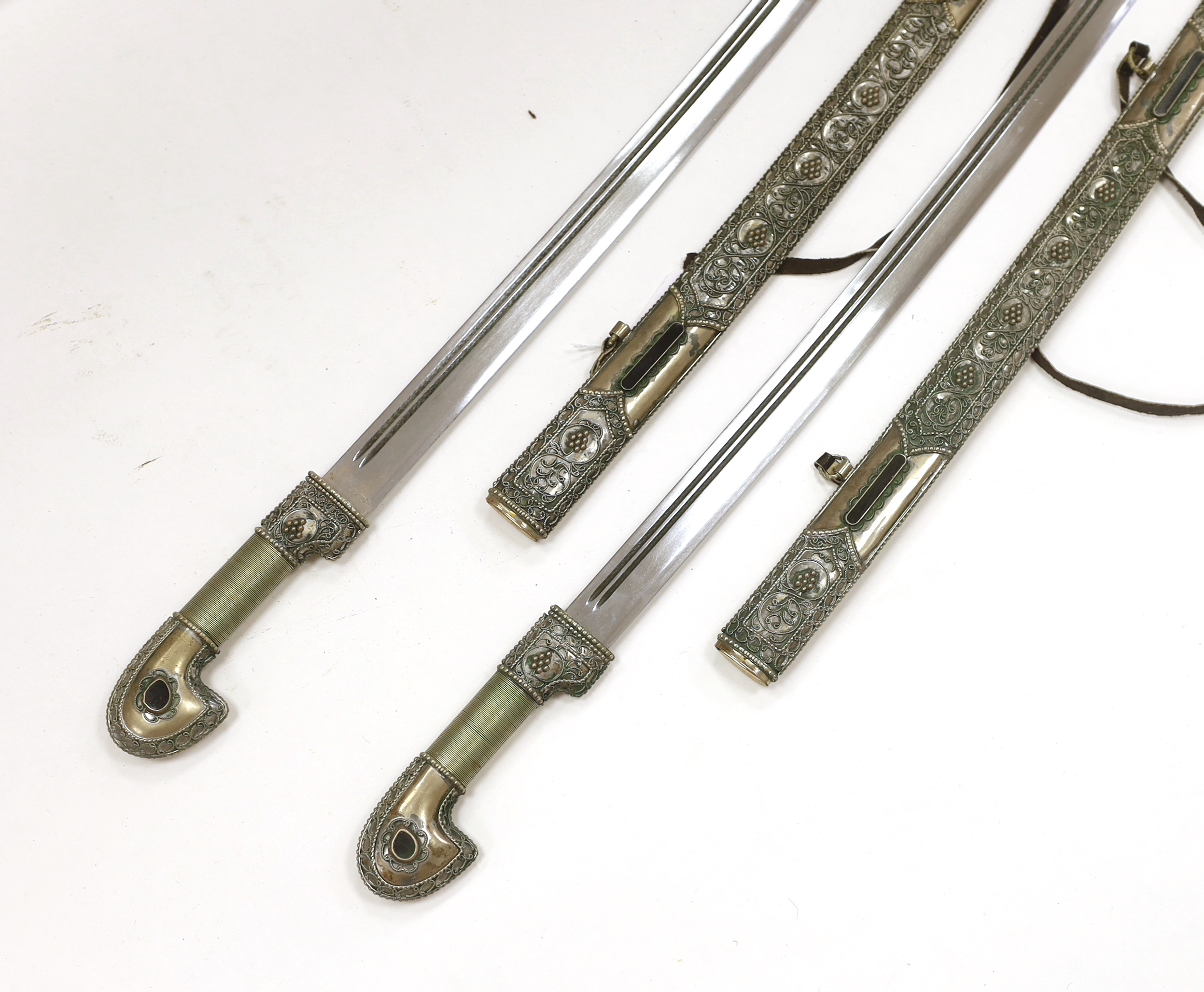 A pair of reproduction Turkish swords with white metal filigree scabbards, blades 80cm